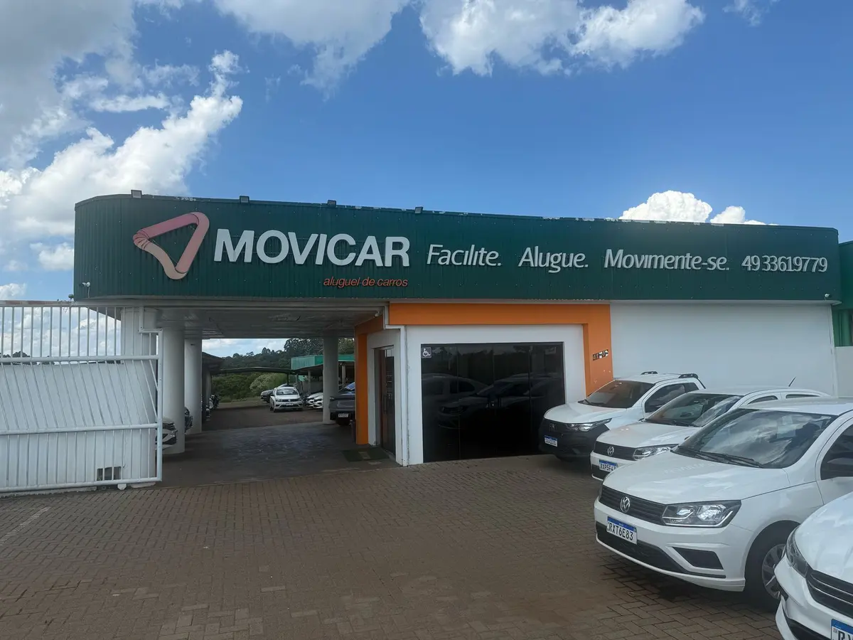 Fachada da loja Movicar, verde, com carros brancos estacionados na frente