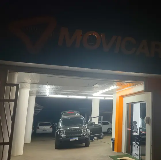 A loja da Movicar à noite, com a garagem iluminada e um carro pronto para sair
